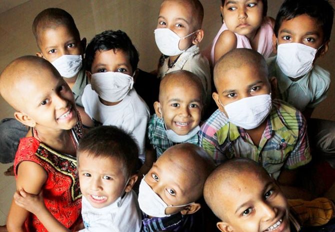 Children in face masks smiling up at the camera